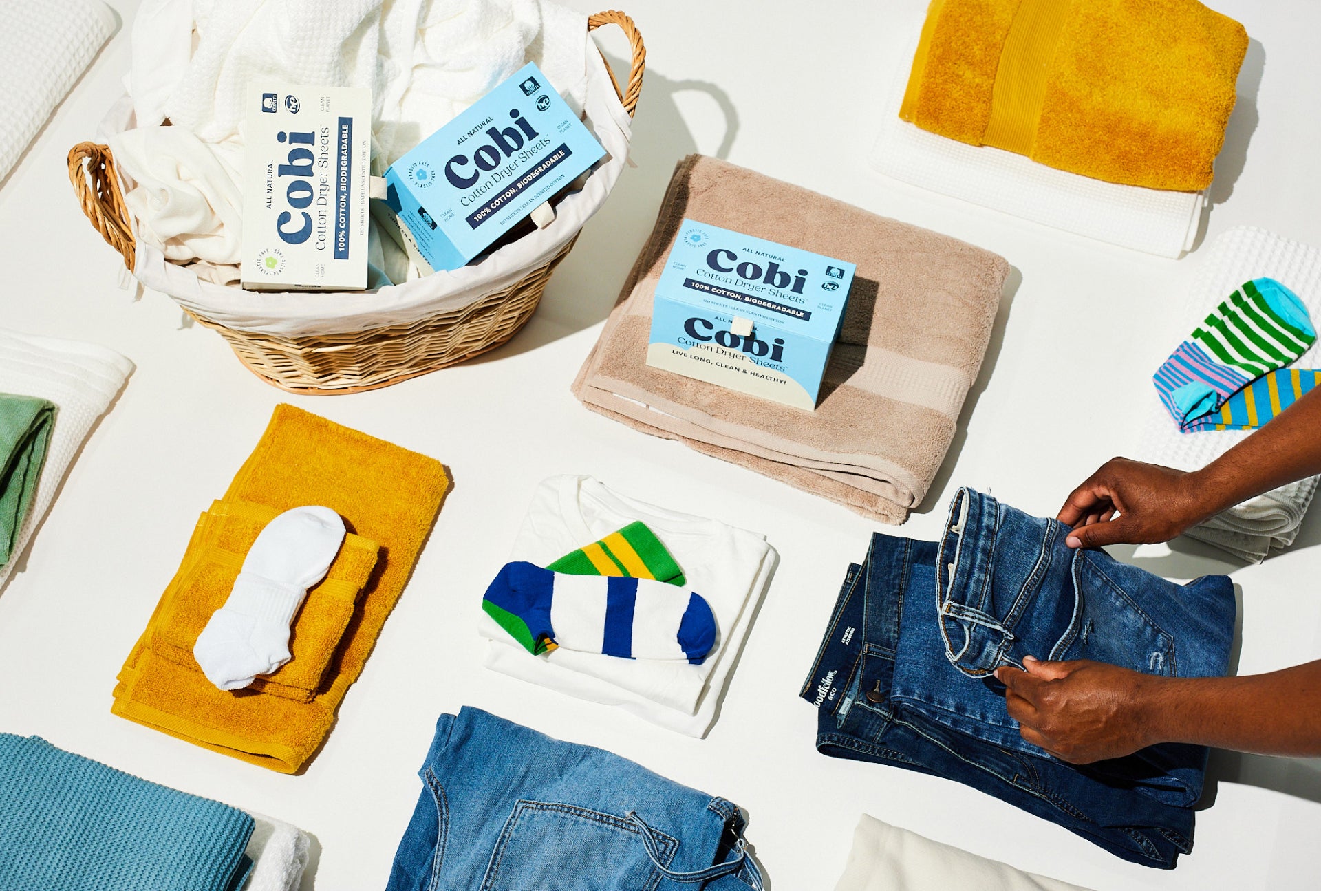stacks of colorful folded laundry and boxes of Cobi dryer sheets